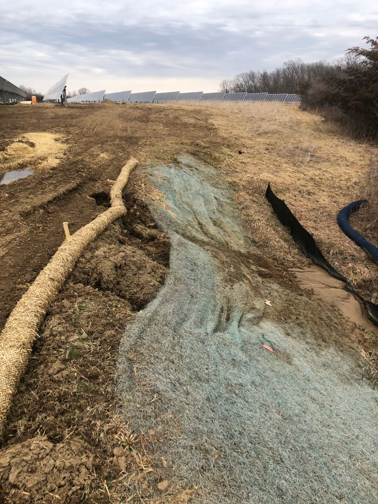 Erosion control measures on a muddy construction site. Straw wattles and erosion control fabric are visible.