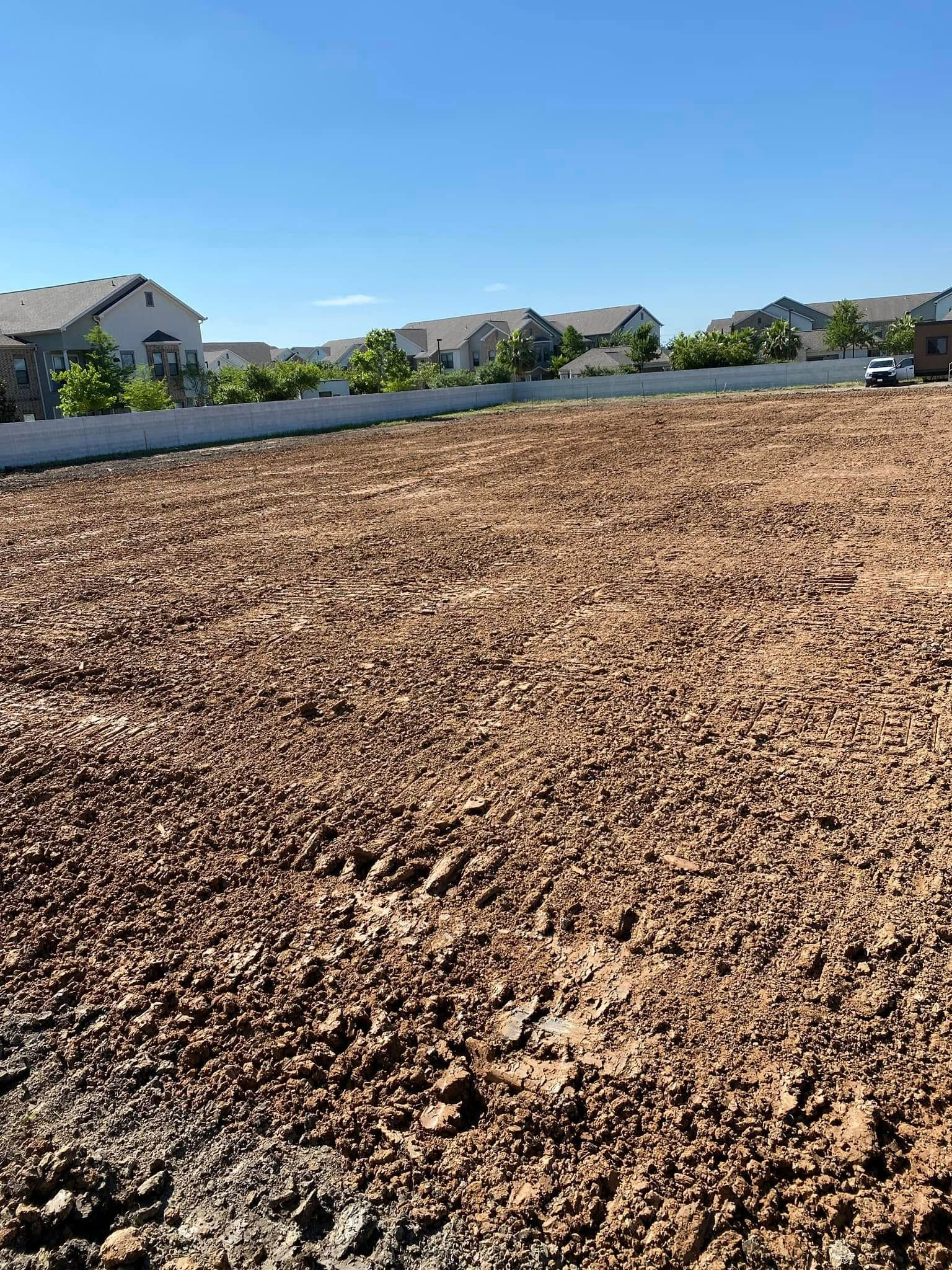 Brown dirt lot with houses and blue sky background.