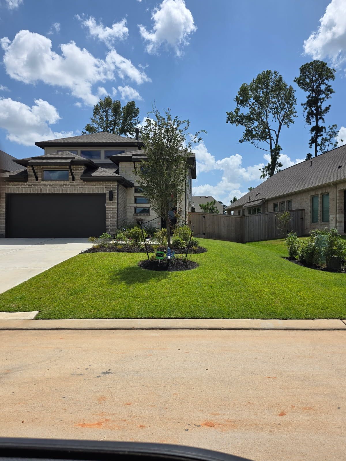 Suburban home with a two-car garage, green lawn, and partly cloudy blue sky