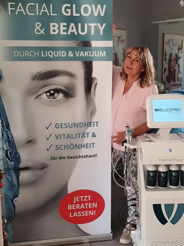 Eine Frau steht vor einem Schild mit der Aufschrift „Gesichtsglanz & Schönheit“