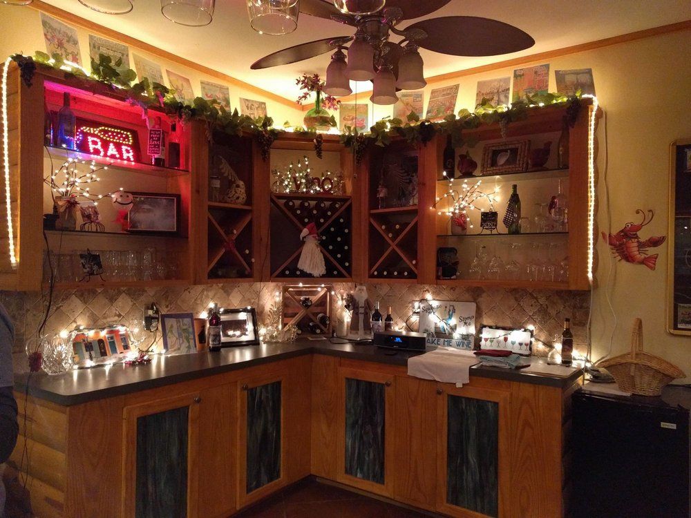 Cozy home bar with wooden cabinets, lit with fairy lights and a neon