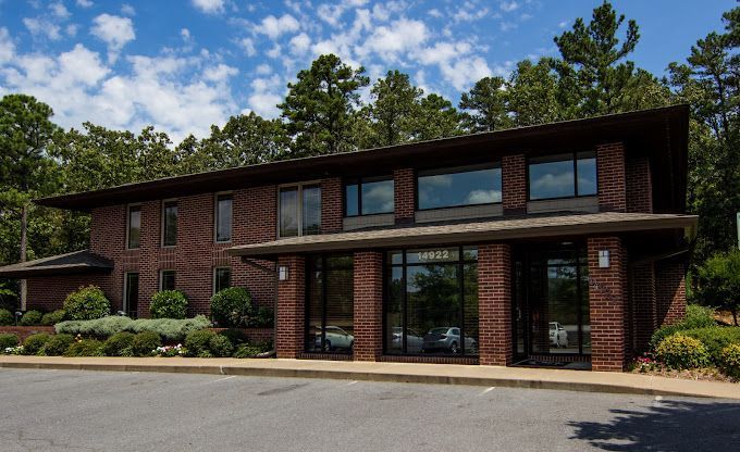 a large brick building with a lot of windows is surrounded by trees .