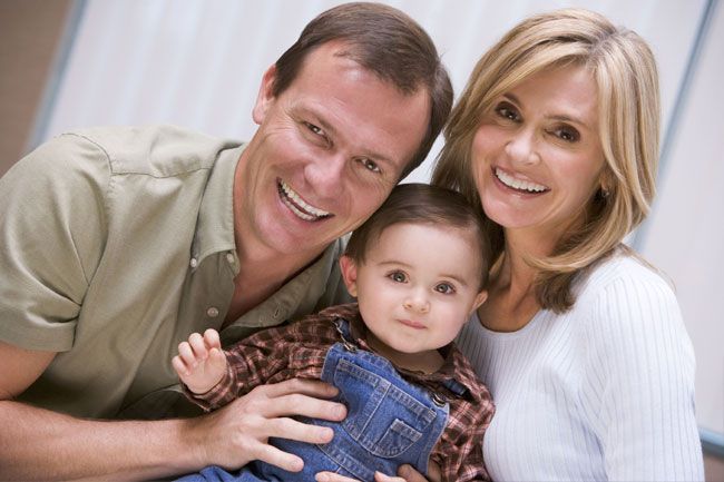 a man and woman are holding a baby and smiling for the camera .