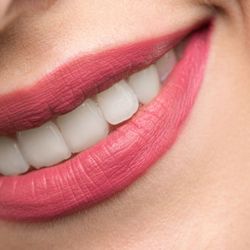 a close up of a woman 's mouth with white teeth and pink lipstick .