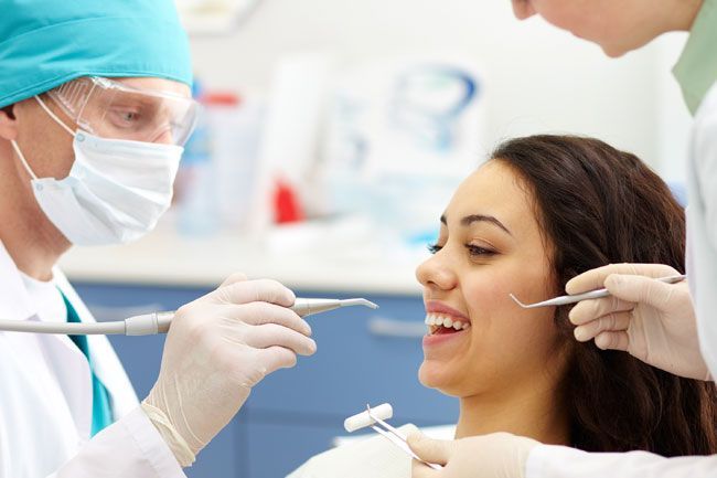 a woman is sitting in a dental chair while a dentist examines her teeth .