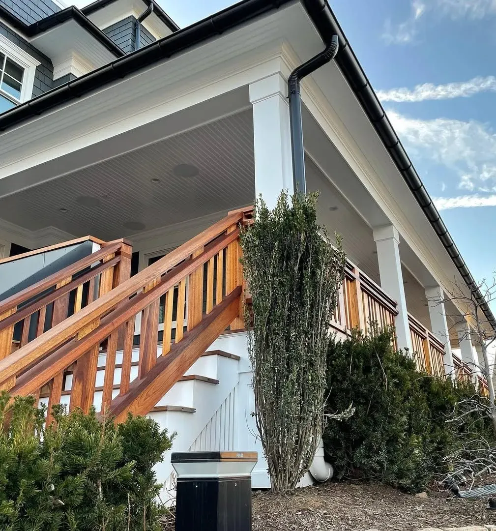 Wooden staircase leading up to a white porch with a black roof and gutter.