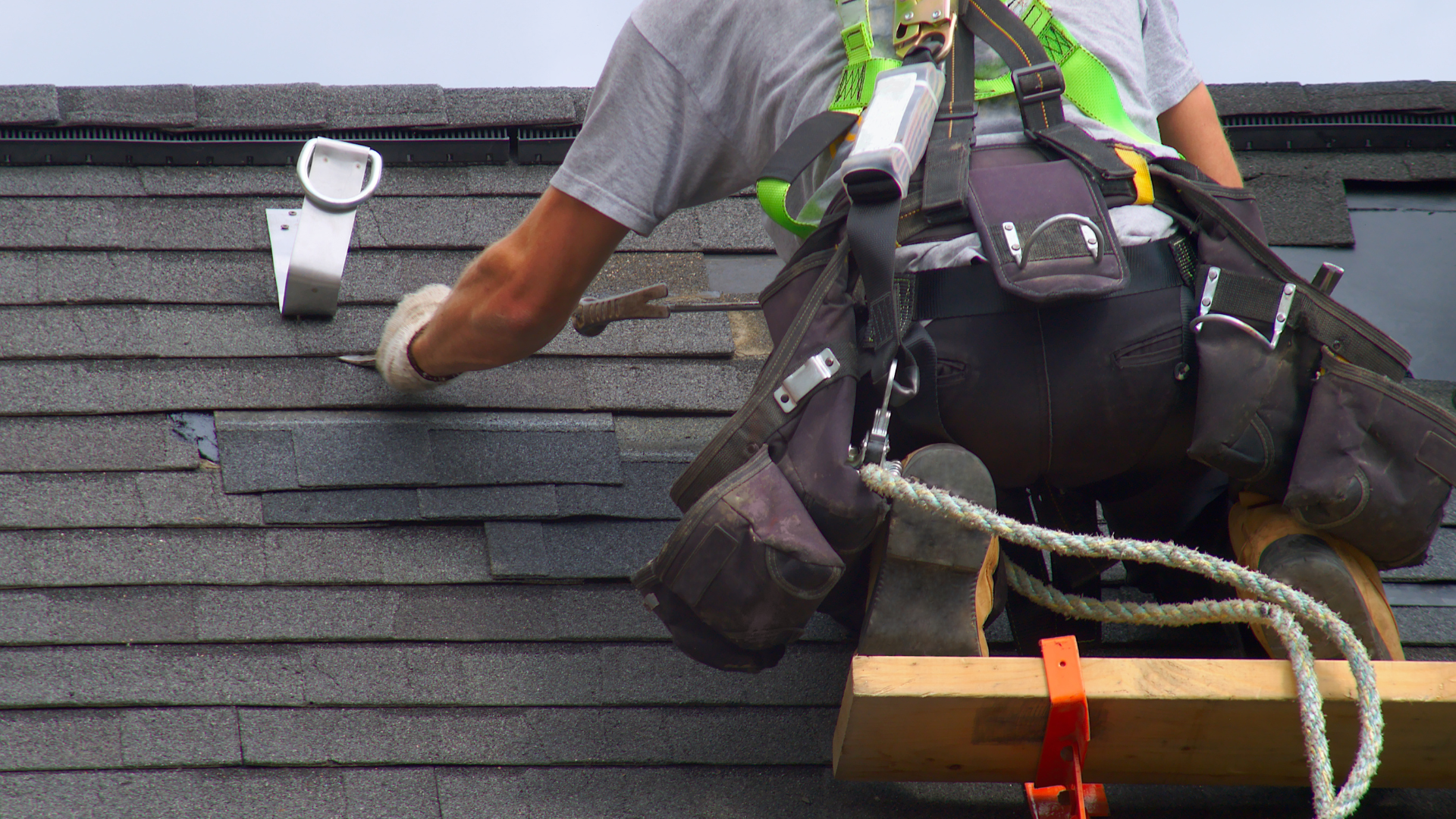 Roof worker doing roof repair, new shingles are darker than the old ones