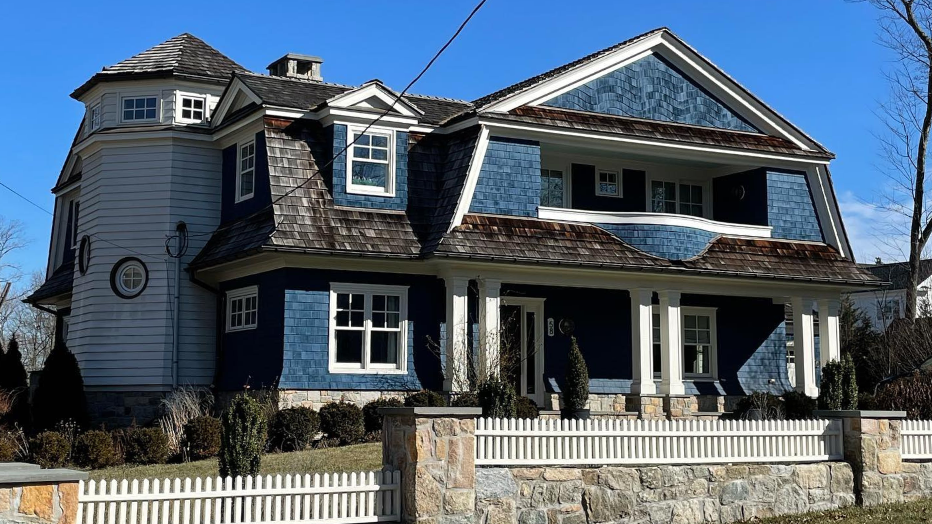 Large blue Victorian house with white trim, porch, and picket fence, a project of Paese Construction LLC