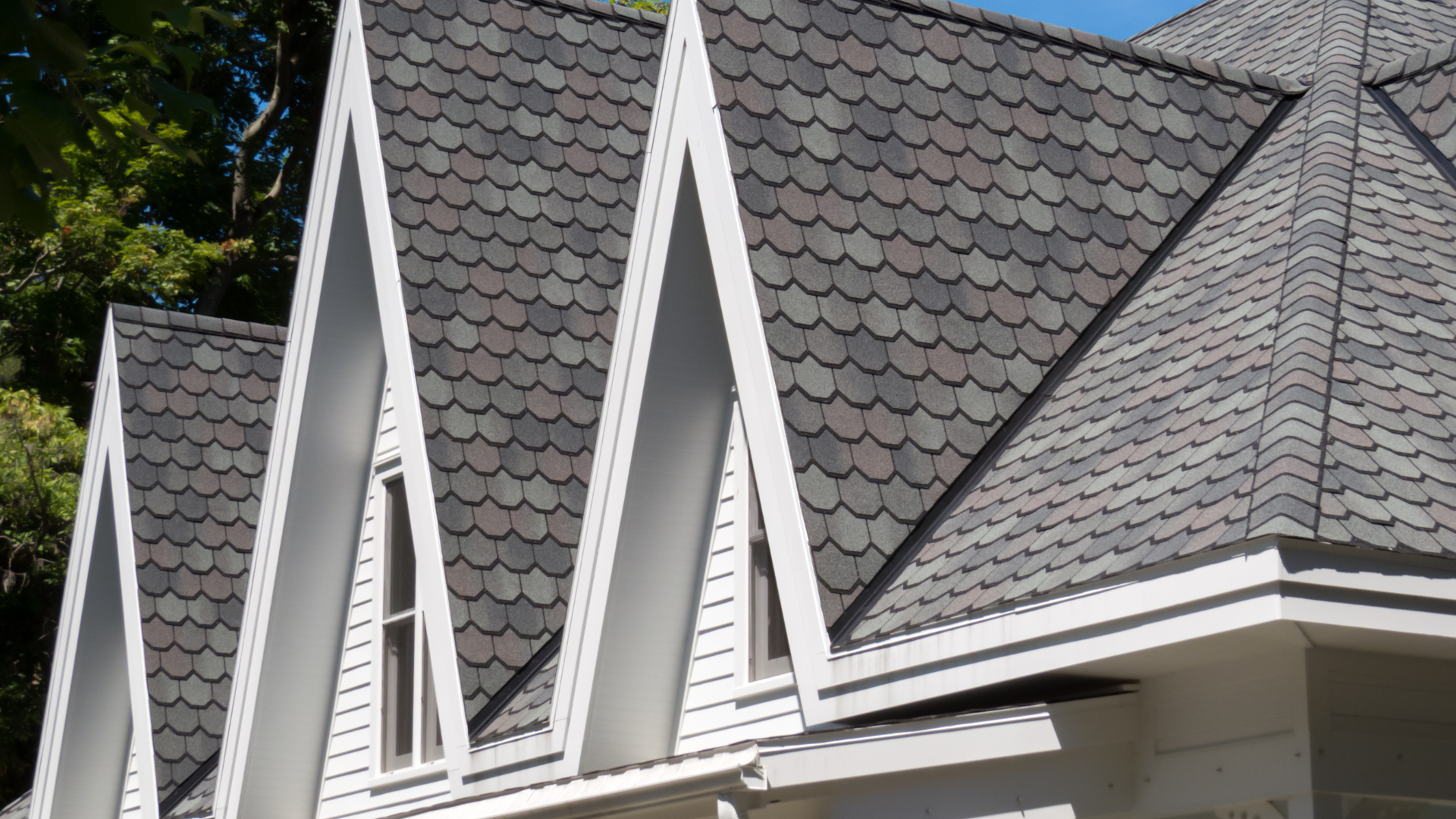 Row of white-trimmed dormer windows with gray shingle roofs and flashingon a house