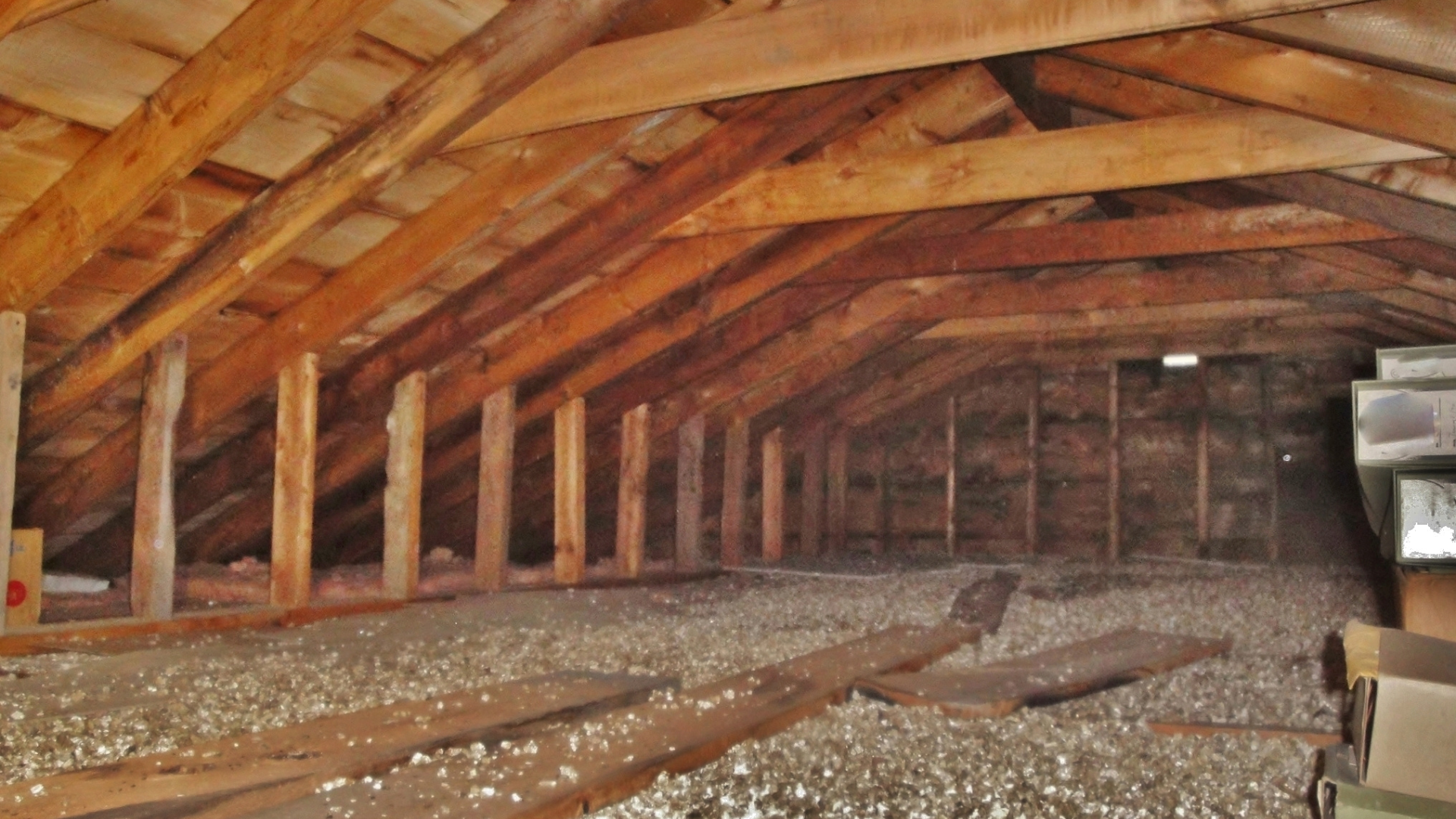 Empty wooden attic with exposed beams and insulation on the floor.