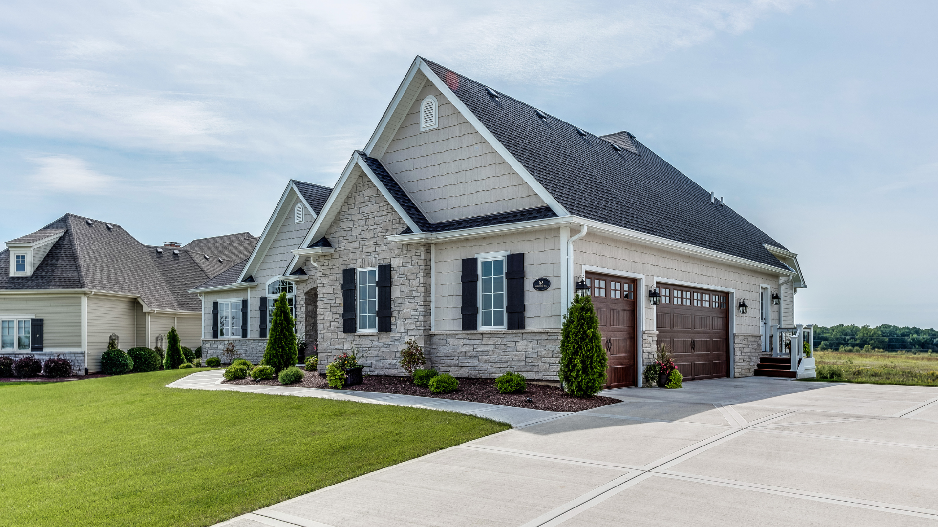 Modern single-story stone house with new roof, garage, and driveway with good curb appeal in a suburban neighborhood