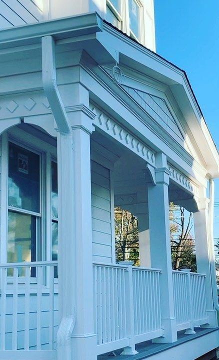 A white house with a porch and a blue sky in the background