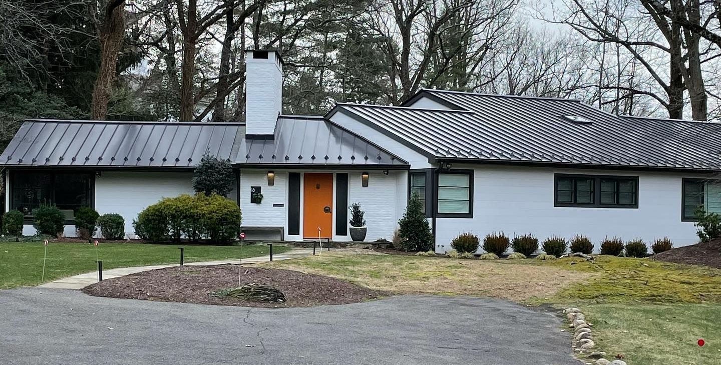 A white house with a metal roof and an orange door
