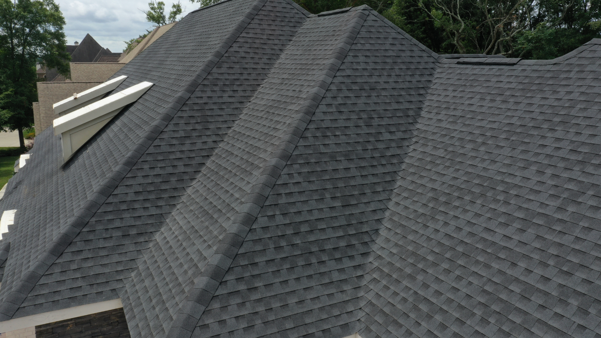 Dark gray shingled roof with multiple steep slopes and two skylights