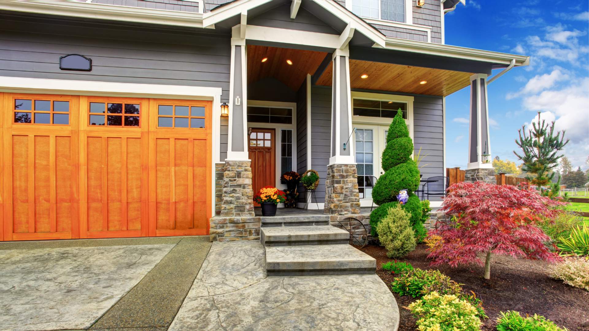 Modern house exterior with orange garage door, stone steps, and landscaped front yard