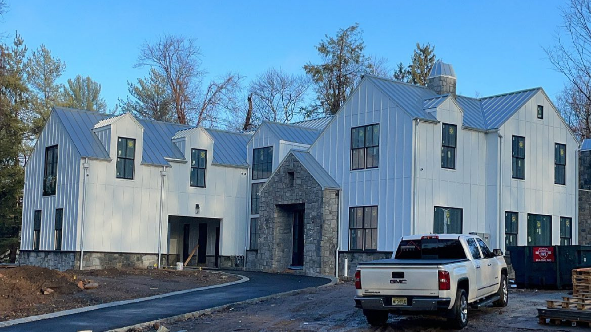 New white multi-story house under construction with a stone entry and a white pickup truck in front