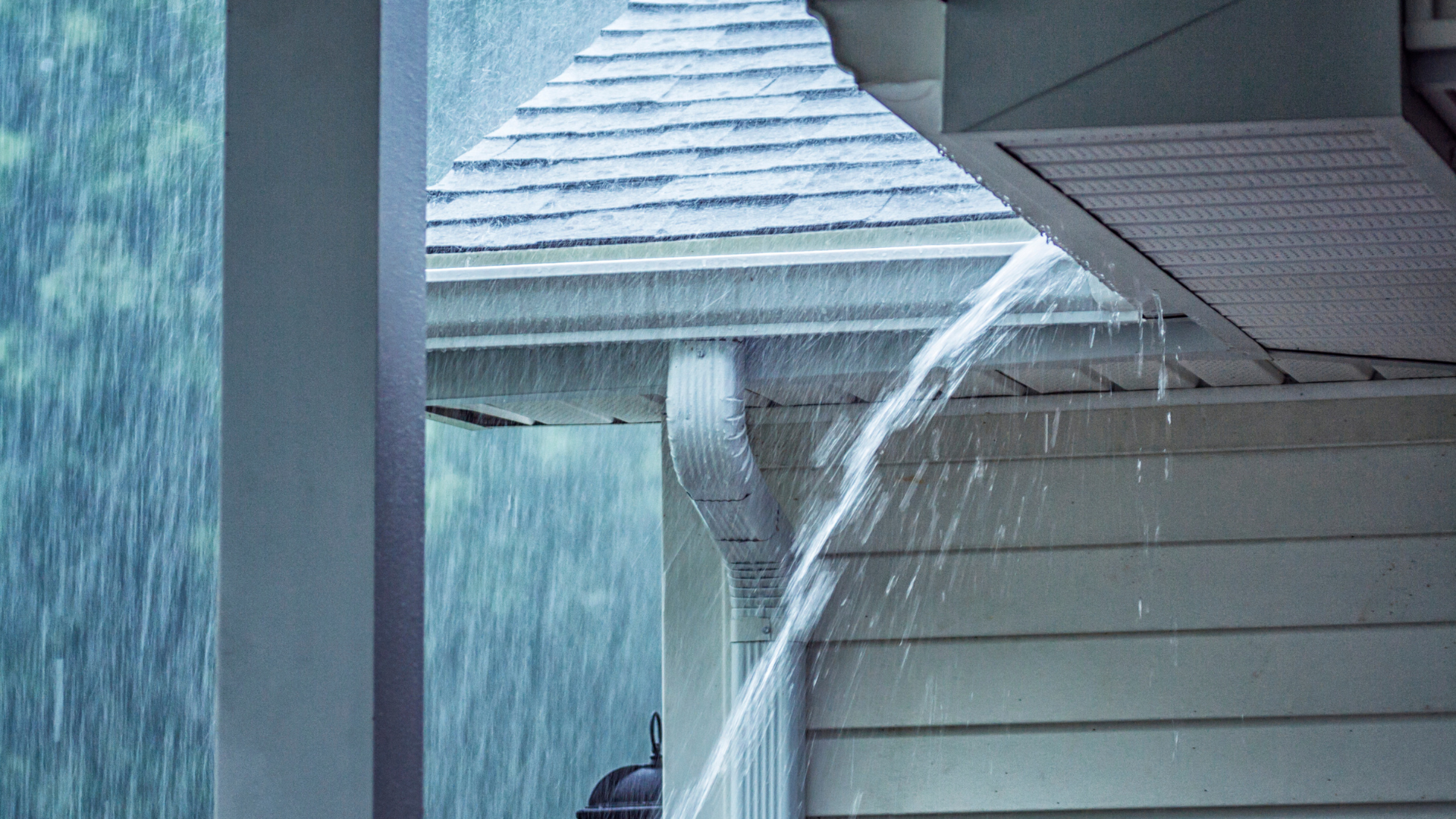 Heavy rain pouring off a roof over a house exterior