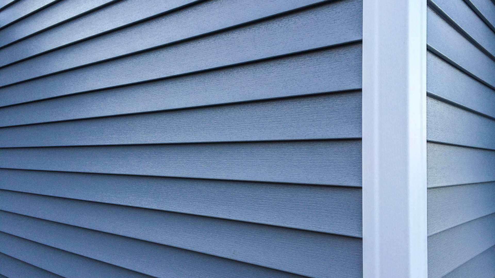 Blue-gray house siding with white trim at an exterior corner