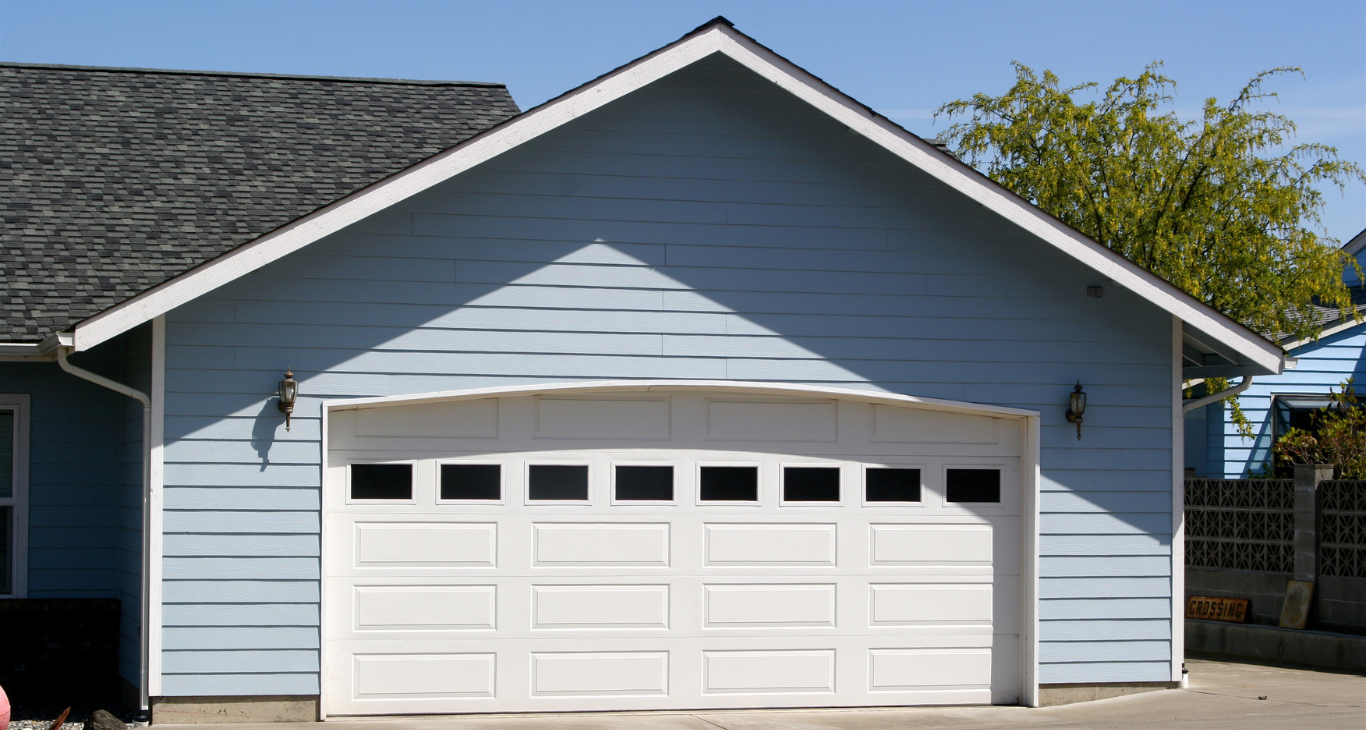 A blue house with a white garage door and a black roof