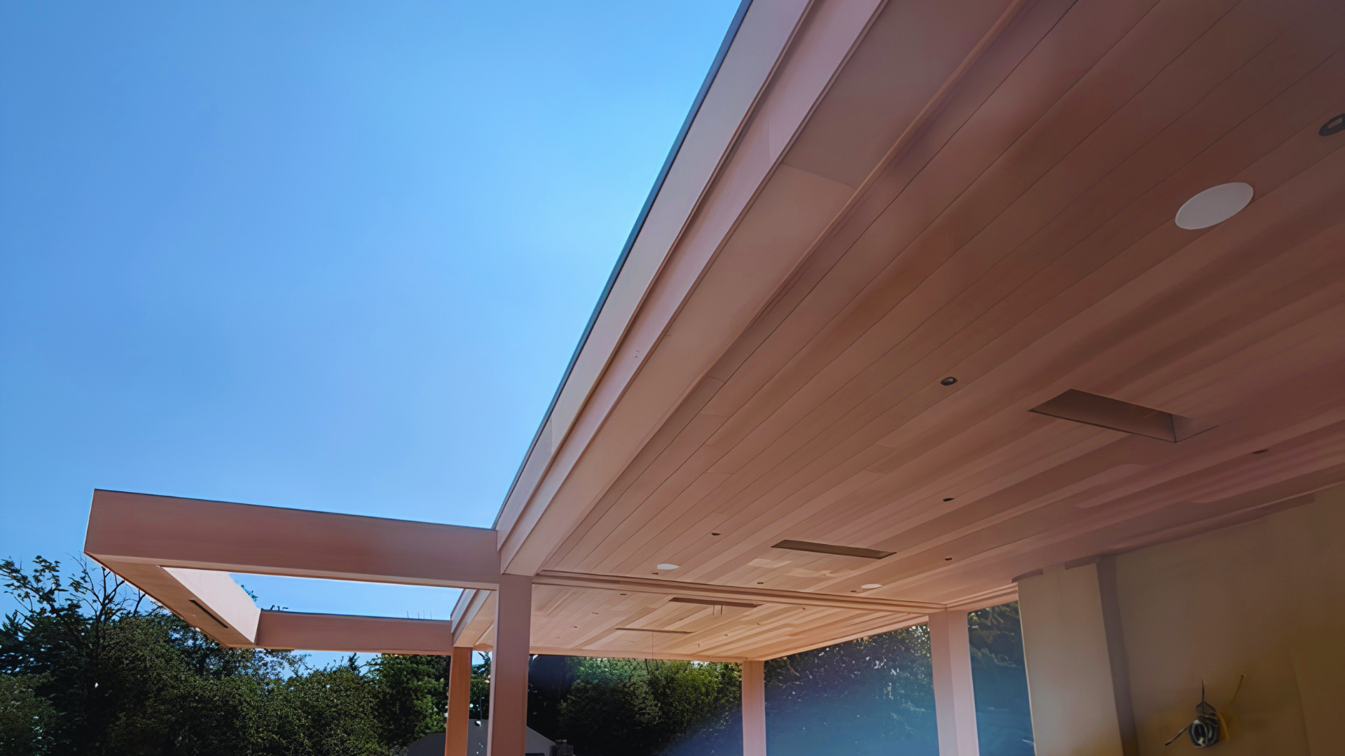 Modern house patio with wooden overhang and blue sky at dusk