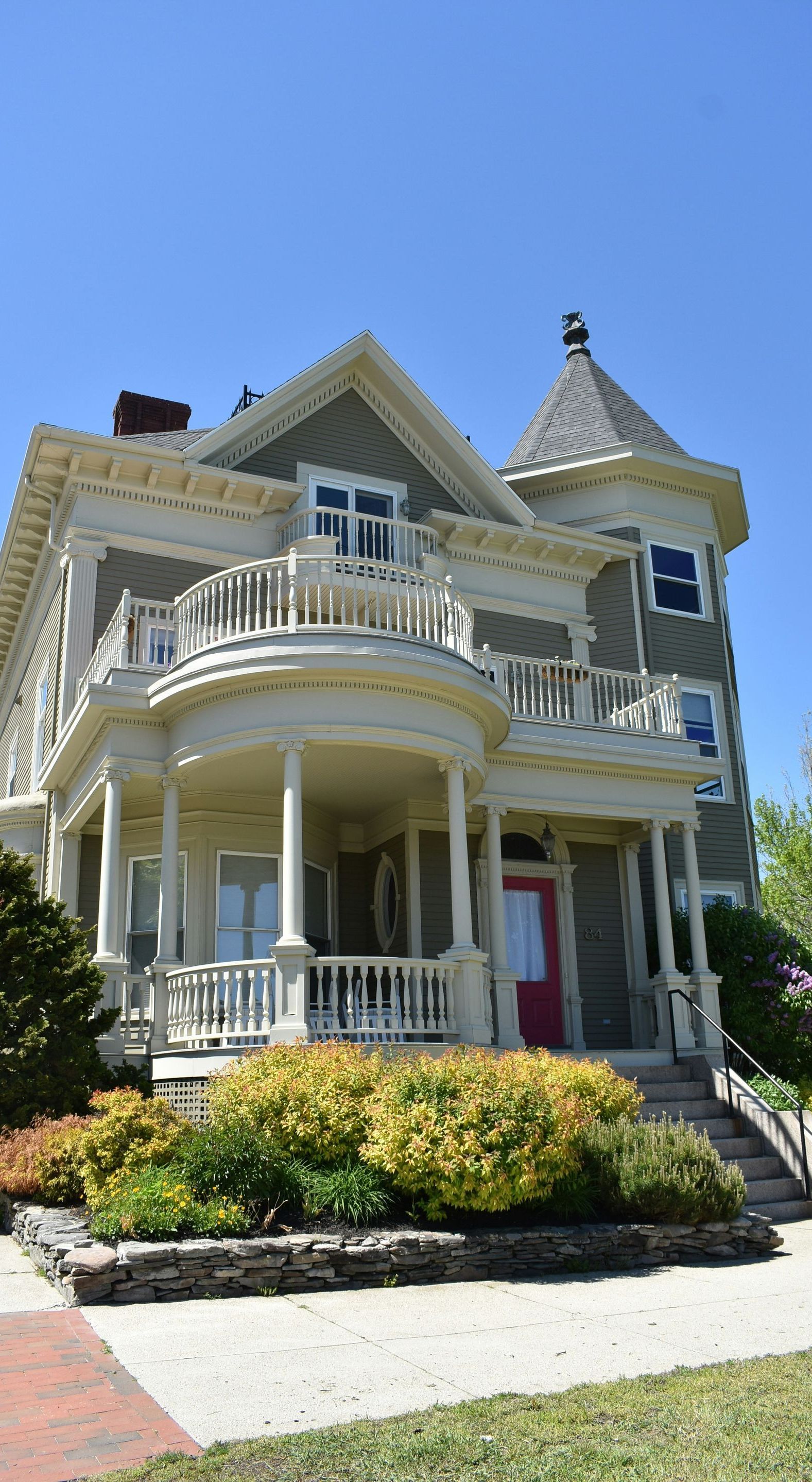 A large house with a large porch and a red door.