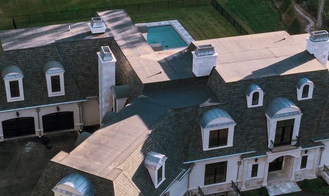 An aerial view of a large house with a pool on the roof