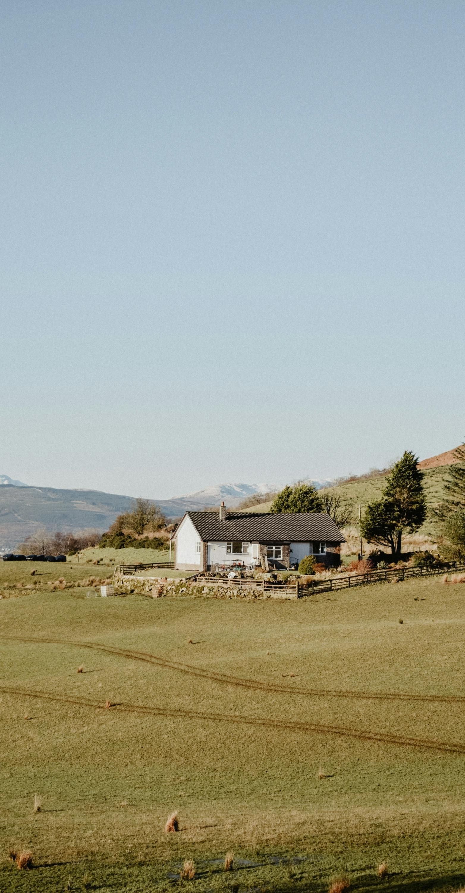 A white house is sitting in the middle of a grassy field.