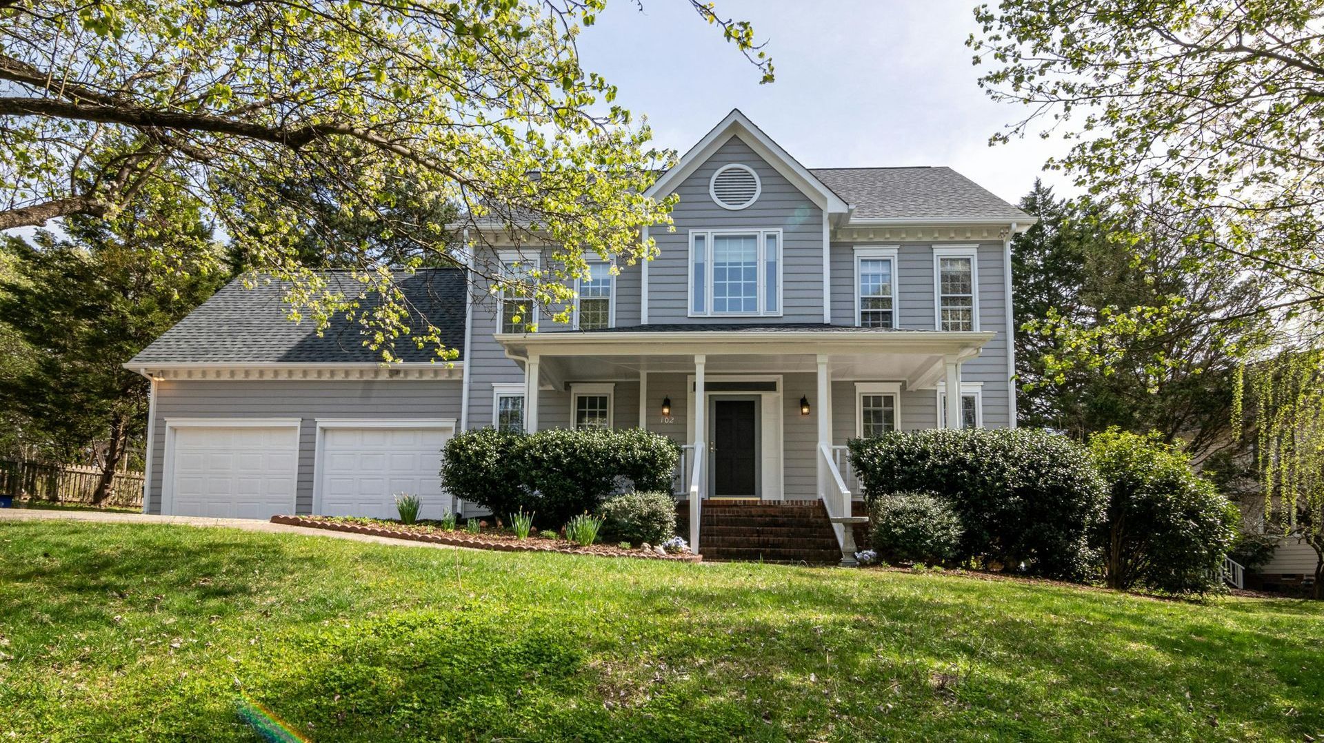 A large house is sitting on top of a lush green hill.