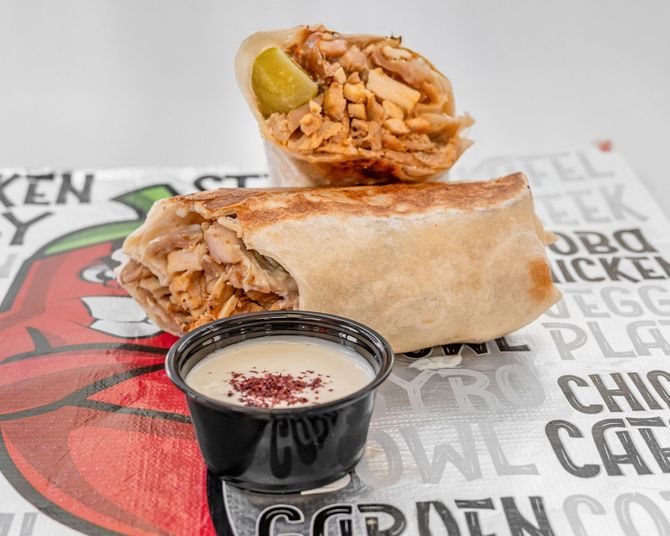 Shawarma wrap cut in half, with dipping sauce.