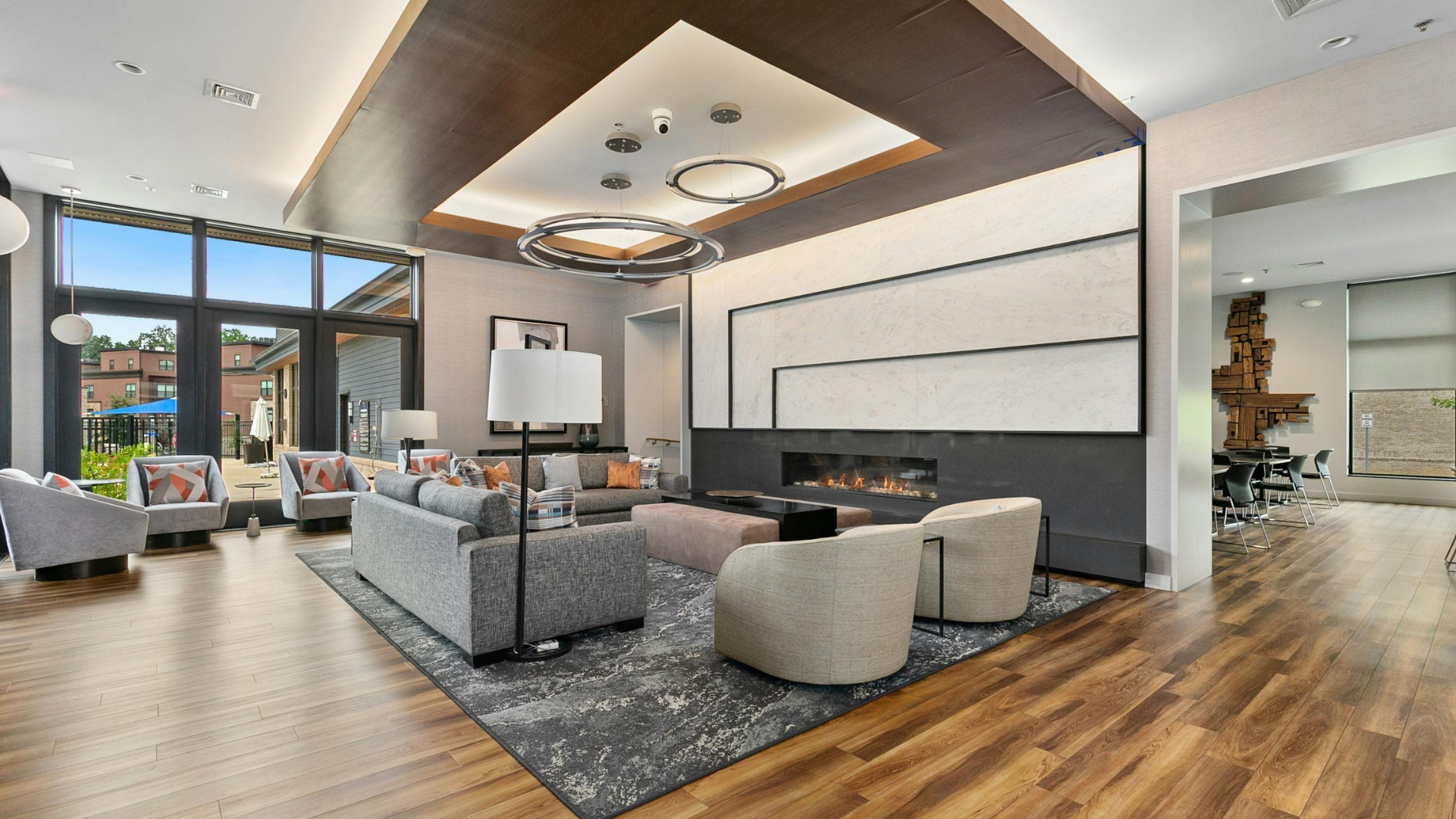 A modern lobby with a fireplace, seating area, large windows, and decorative lighting.
