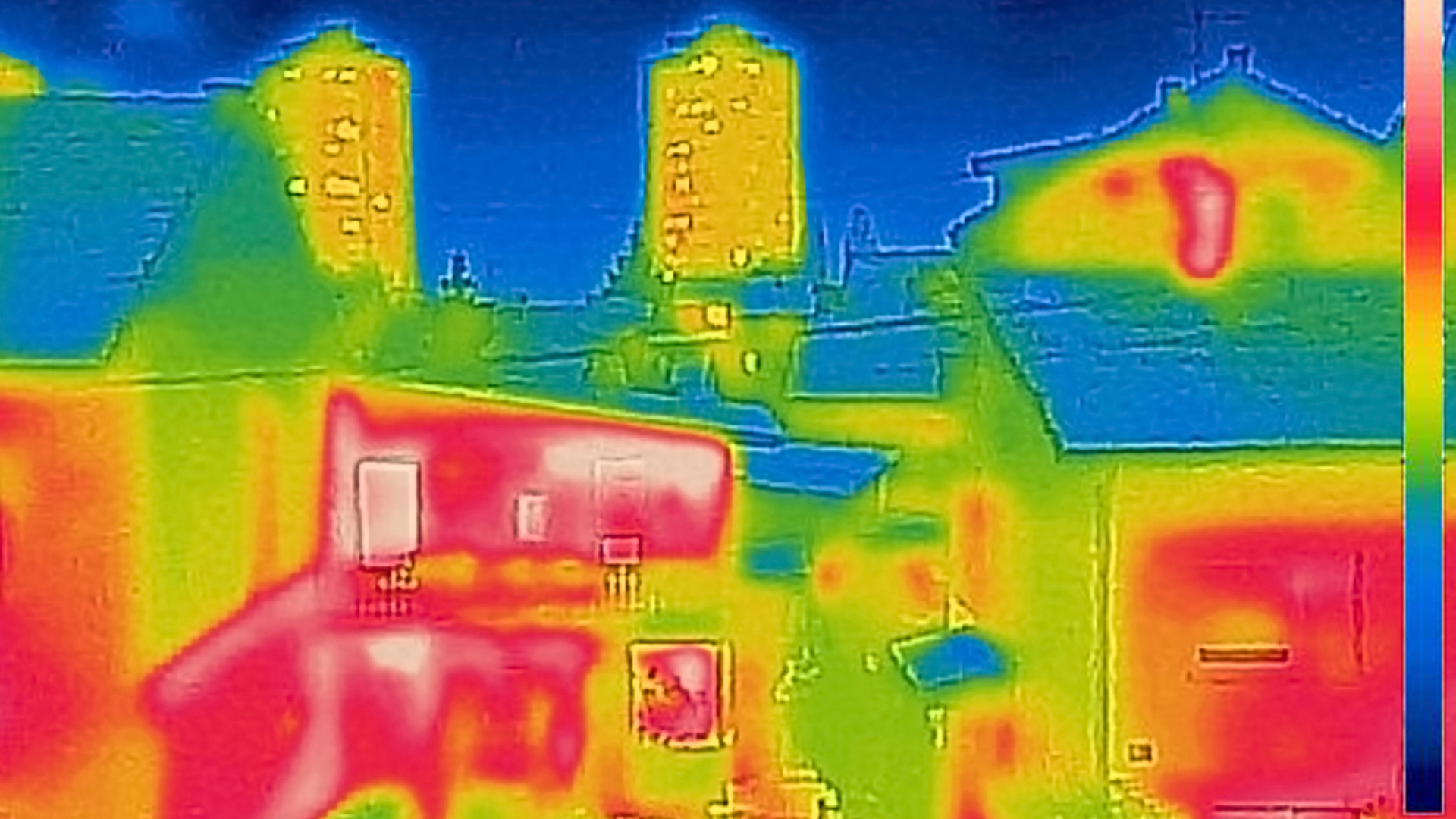 Thermal-style view of buildings and trees in bright red, yellow, green, and blue colors.