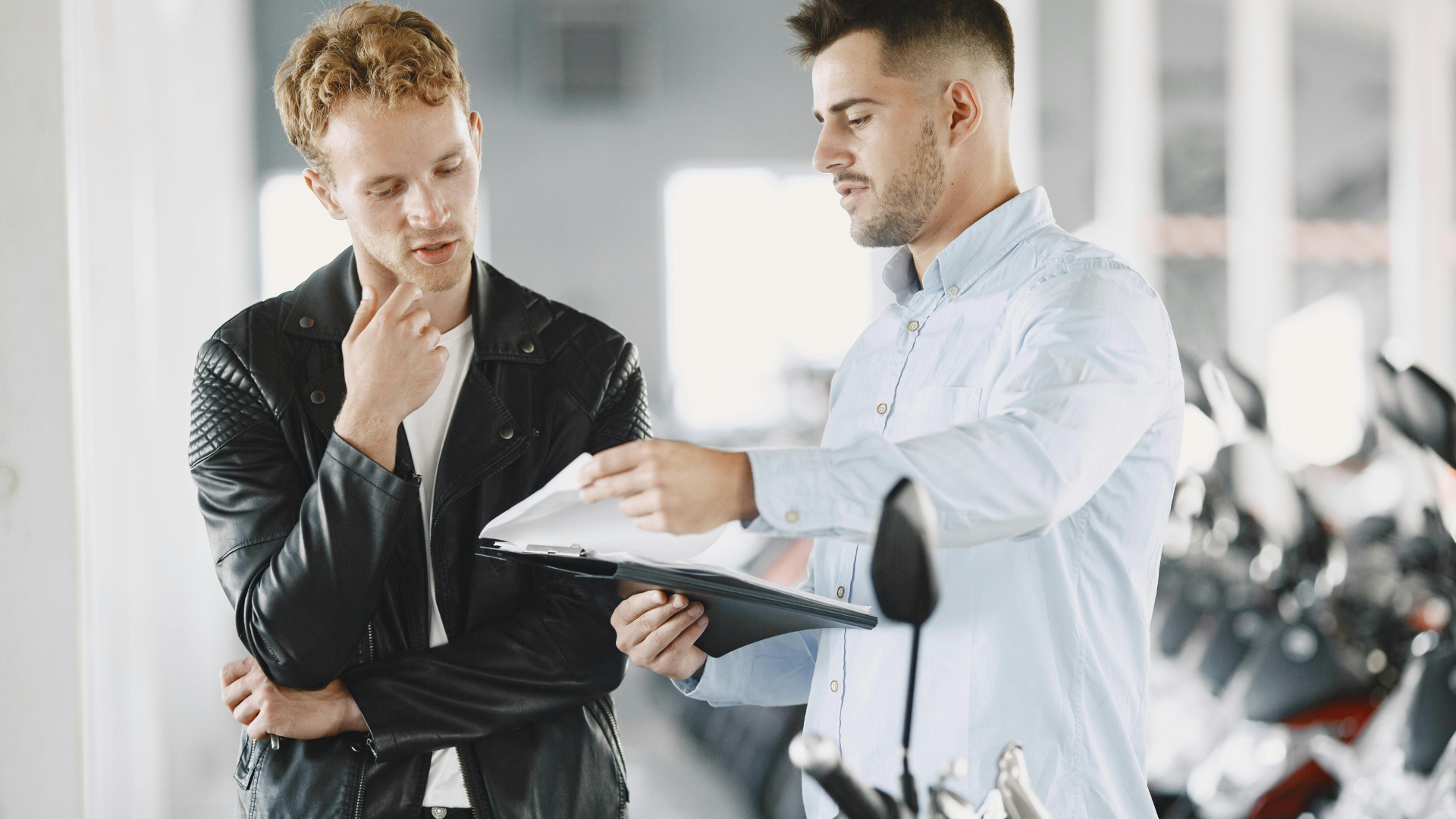 Two men reviewing a notebook together in a bright office setting