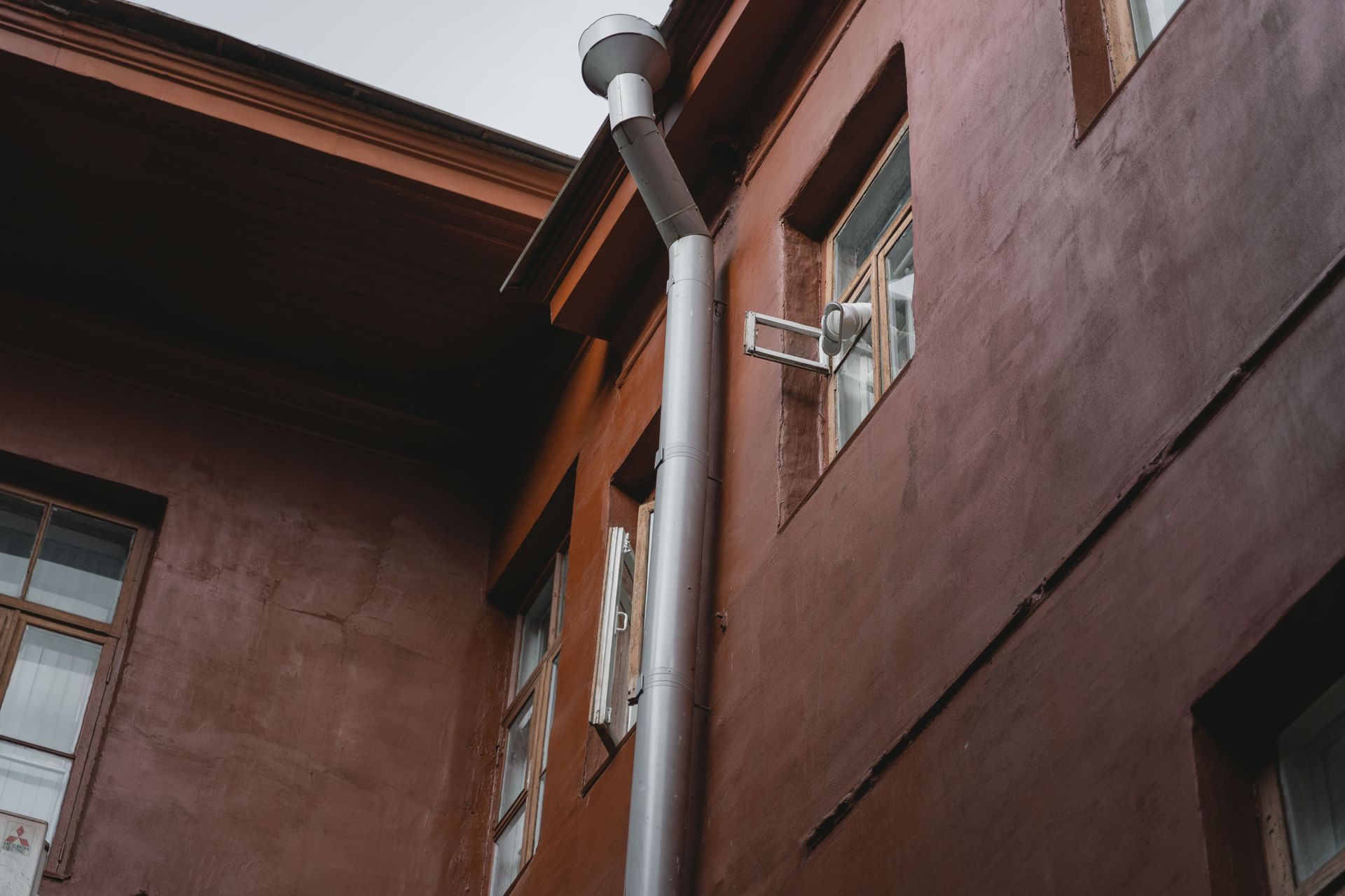 Brown building exterior with metal downspout and windows