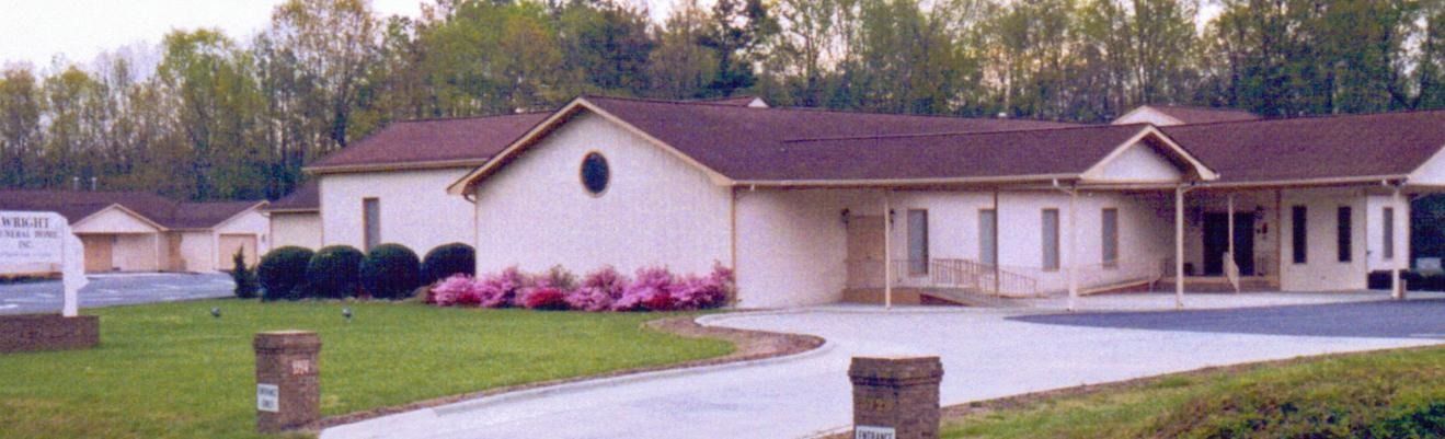 Single-story beige house with a curved driveway, front porch, and pink flowers in the yard