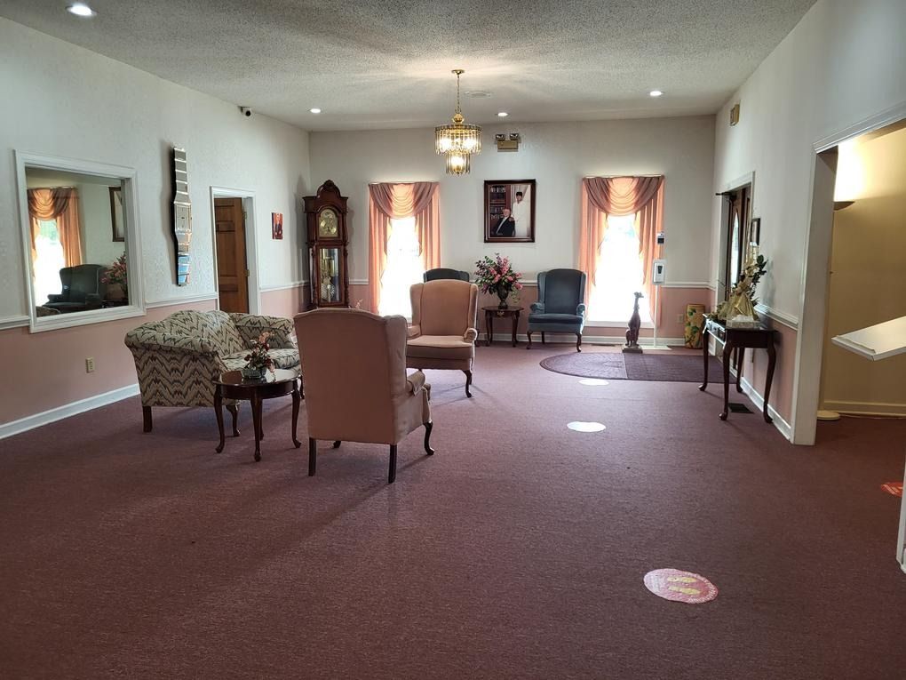 Spacious lobby with mauve carpet, patterned chairs, ceiling lights, windows, and framed artwork.