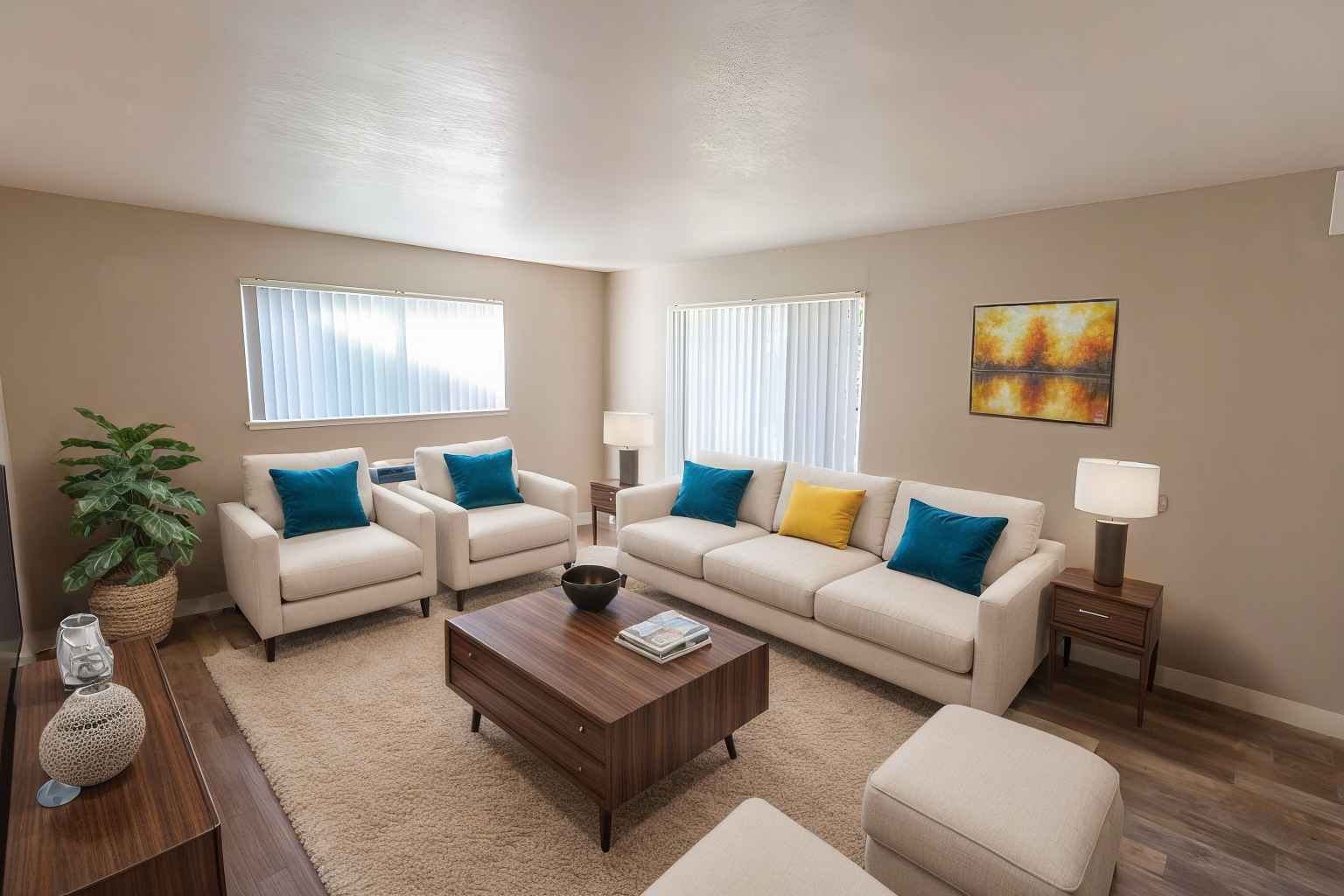 Bright living room with beige sofas, teal and yellow pillows, wooden coffee table, lamp, and wall art.
