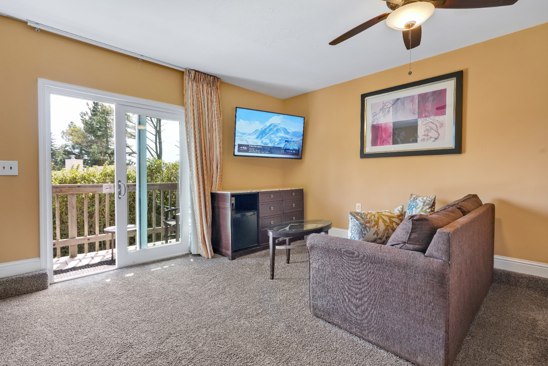 A living room with a couch a television and a ceiling fan
