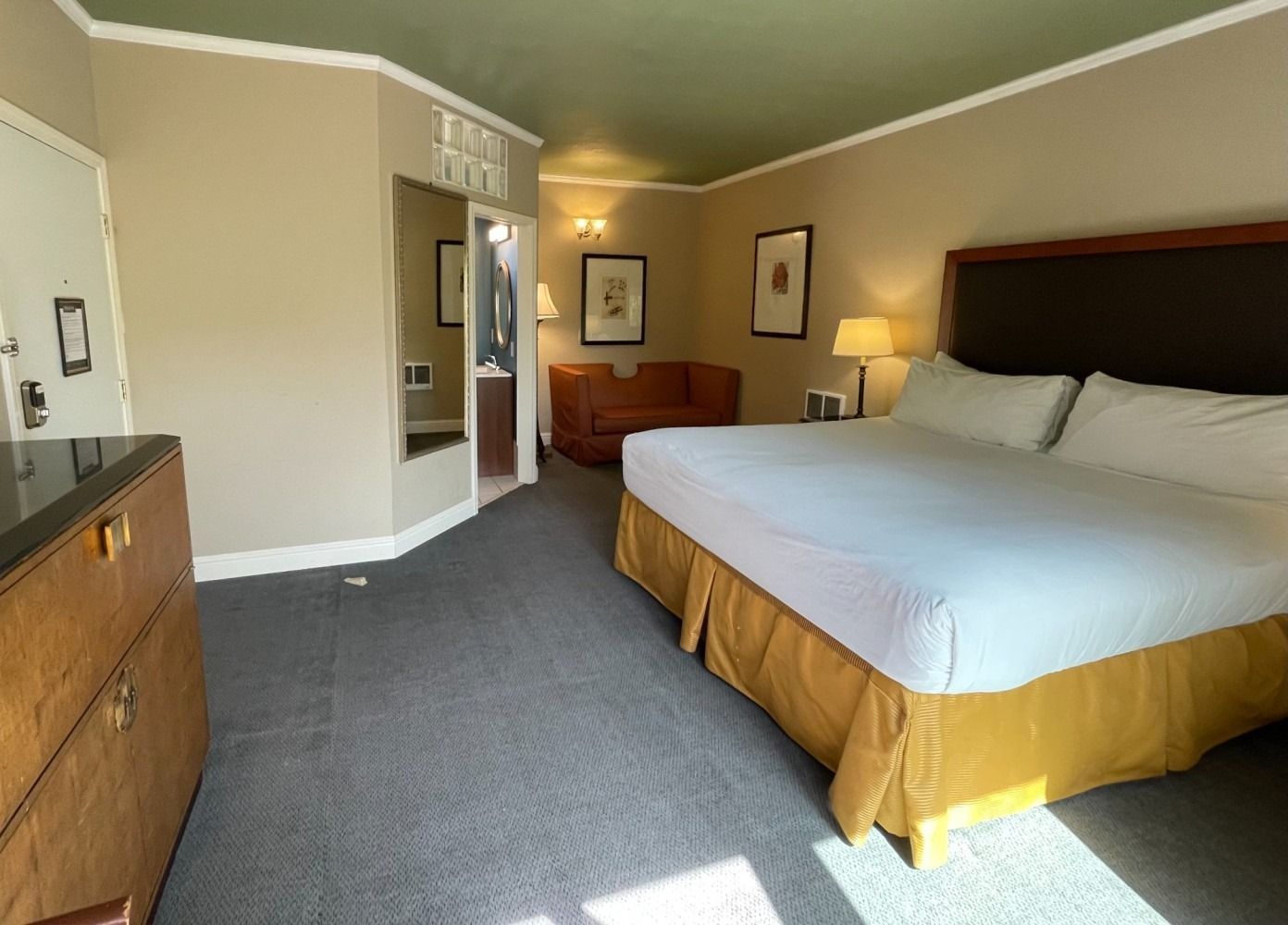 A hotel room with a king size bed and a dresser.