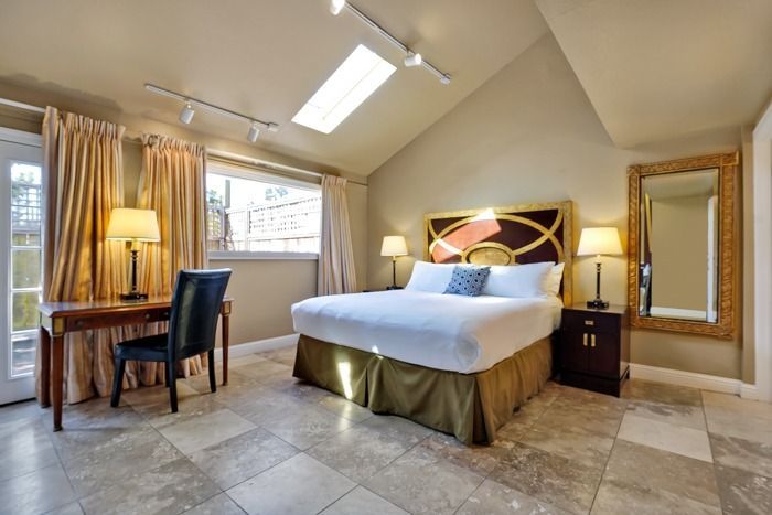 A hotel room with a king size bed , desk , chair and mirror.