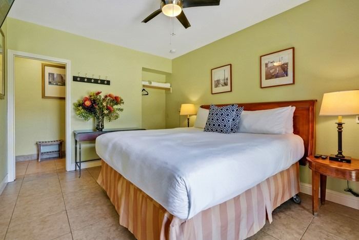 A hotel room with a king size bed and a ceiling fan