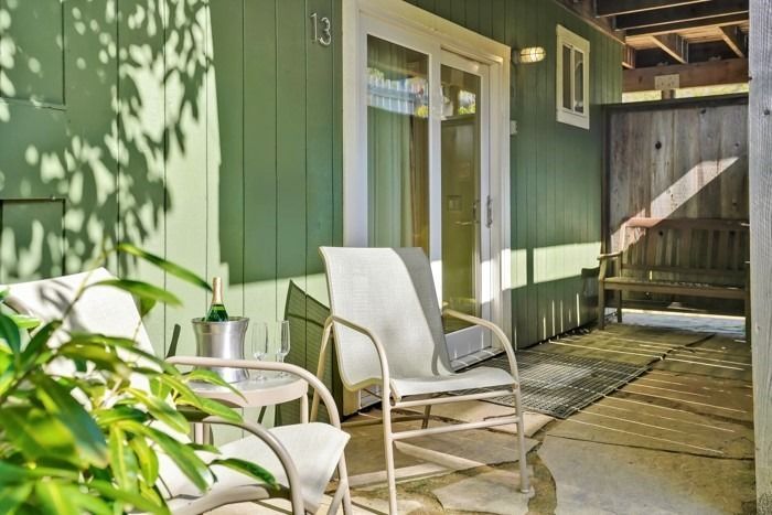 A patio with two chairs and a table with a bucket of champagne on it.