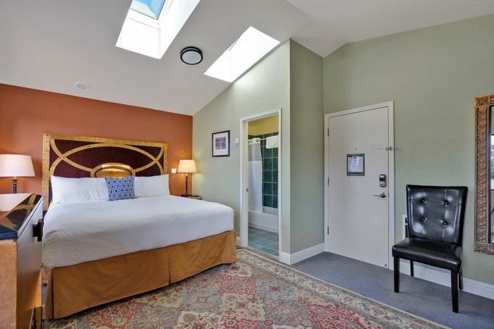 A hotel room with a king size bed and a chair.