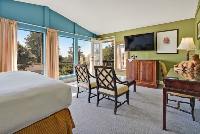 A hotel room with a bed , chairs , desk and television