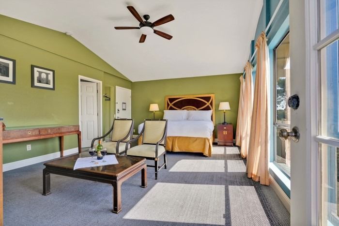 A bedroom with green walls and a ceiling fan