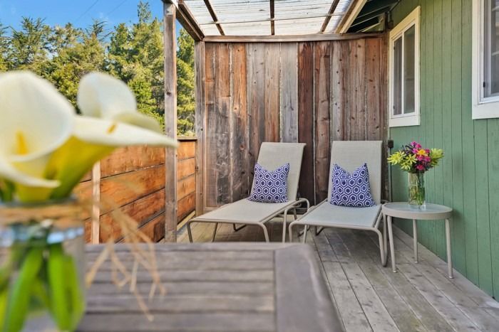 There are two lounge chairs on the deck of a house.