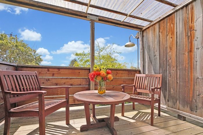 A wooden deck with a table and chairs and a vase of flowers.
