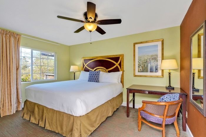 A hotel room with a king size bed and a ceiling fan