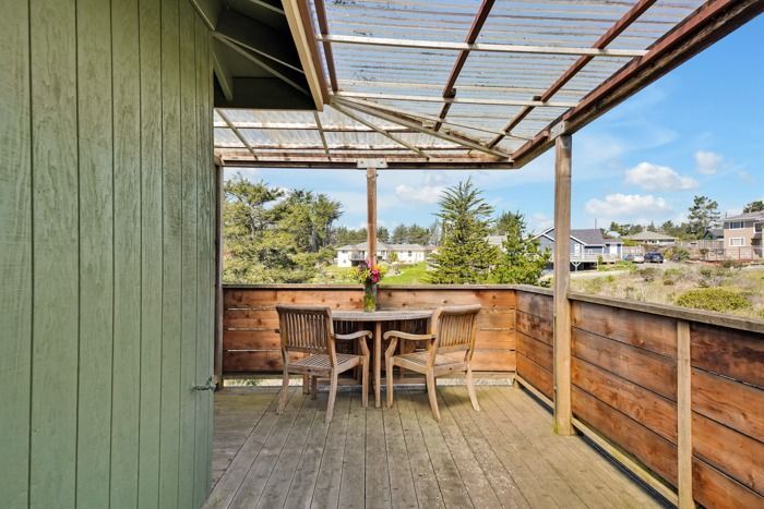 A wooden deck with a table and chairs under a clear roof.