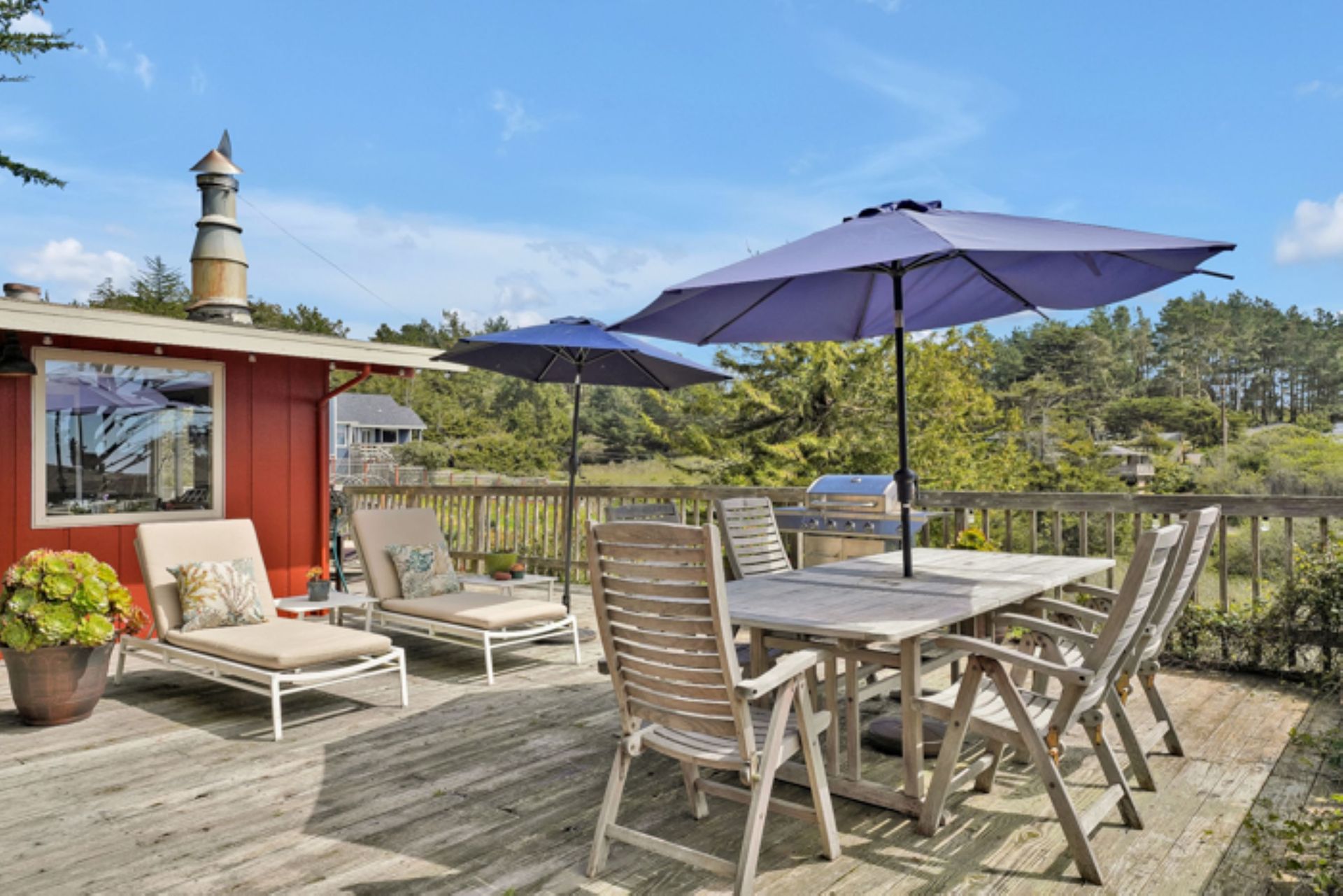 A deck with a table and chairs and purple umbrellas