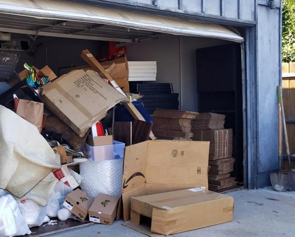 Open garage filled with boxes, furniture, and other items.